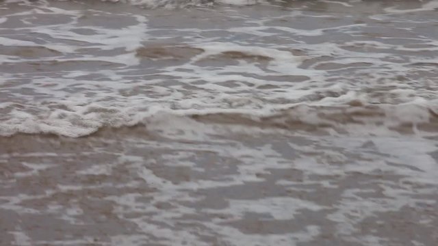 Lapping tidal waves on shoreline with as the ocean water ebbs and flows.