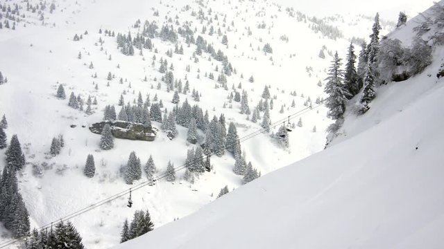 Time lapse of a ski chair lift in the resort of Praz sur Arly, with trees and mountain background.