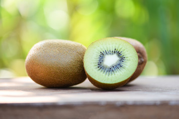kiwi slices close up and fresh whole kiwi fruit on wooden and nature green background