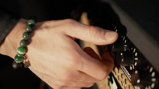 The musician turns up the volume, amplifer, bracelet guitar.