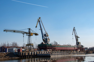 Fototapeta na wymiar Dry cargo barge with cranes on it against the blue sky and a pair of jets