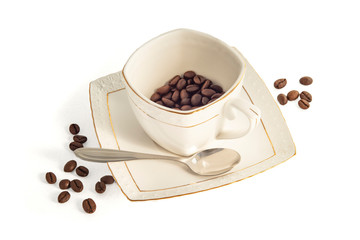 Light Cup with saucer and spoon of chocolate colored coffee beans on white background