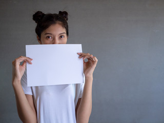 Young asia woman holding blank paper sheet over isolated background scared in shock with a surprise face, afraid and excited with fear expression 