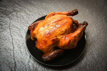 Roasted chicken / baked whole chicken grilled on black plate and dark background on top view