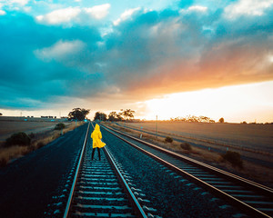 Person in Yellow Jacket on Old Train Tracks With Epic Sky - 266250021