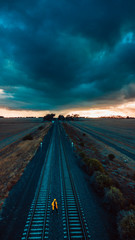 Person in Yellow Jacket on Old Train Tracks With Epic Sky - 266251838