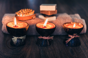 Burning spa aroma candles in coconut shell, handmade soap, towel and washcloth, spa concept background.