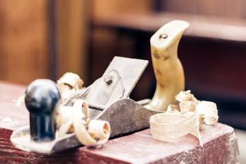 Joinery – old wooden plane and chips in a workshop of the carpenter, retro concept.