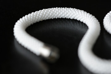 White long beaded necklace on a dark backgroun close up