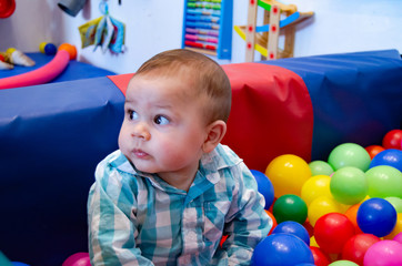 Fototapeta na wymiar Cute six months old baby boy playing with colorful balls in the childcare