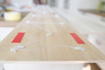 Closeup using construction glue when working with wooden white painted board, carpentry, woodwork,...