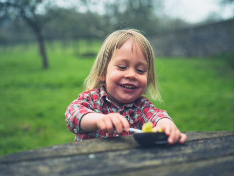 Little toddler eating avocado at picnic table