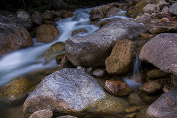 Fototapeta na wymiar Rocks in stream with smooth flowing water