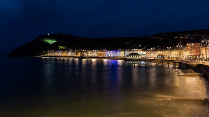 Fototapeta na wymiar Wonderful view of the night seafront of the illuminated Welsh town of Aberystwyth and the mountain in the background.