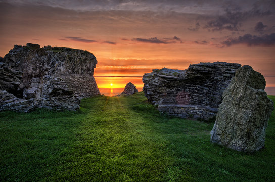 A romantic and beautiful view through the ruins of Aberystwyth Castle on the sunset on the horizon above the sea.