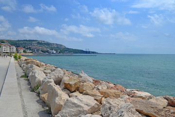 Fototapeta premium Beautiful view of the coast with an artificial mound of stones. Sunny day on the coast of Bulgaria. The road along the sea.