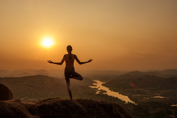 Fototapeta premium Yoga in Hampi temple copyspase at sunset.travel vacation copy spase lady with stylish jumpsuit