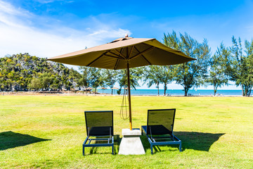 Obraz premium Umbrella and chair on the green grass nearly sea beach