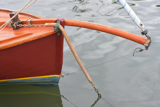 Bow and bent bowsprit with furling headsail of small planked wooden sailing boat on mooring.