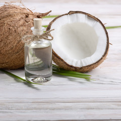 Fototapeta na wymiar Coconut oil in glass jar and shell pieces on white wooden table