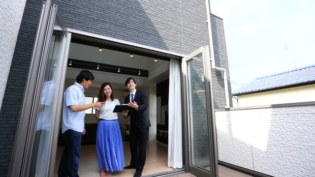 住宅　ビジネスマンと夫婦　内覧　商談　説明　リフォーム　バルコニーから説明