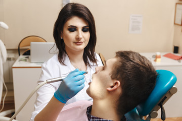 Male patient sitting in the dentist's chair and doctor working