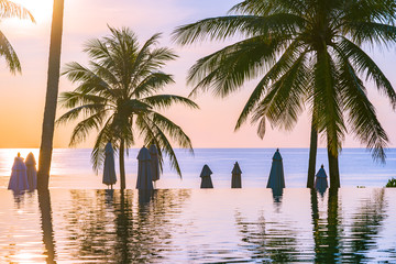 Beautiful outdoor nature landscape with sea ocean and coconut palm tree around swimming pool at sunrsie or sunset