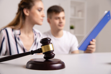 Young renters couple sitting on couch discussing renting apartment with real estate agent, focus on...