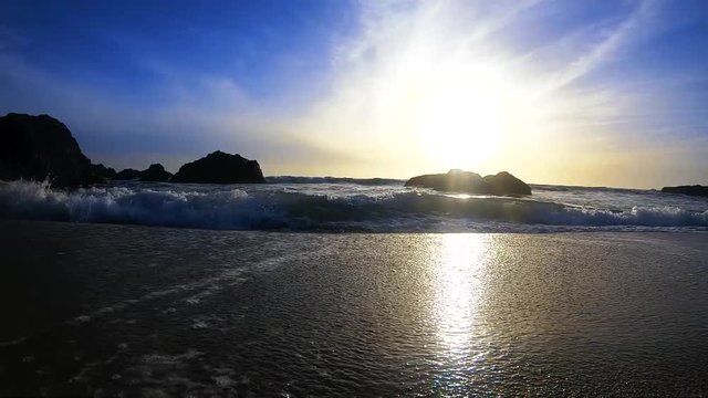 Crashing waves on a beach at sunset filmed in slow motion