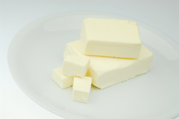 Piece of fresh organic butter on the plate isolated on a gray background in close-up