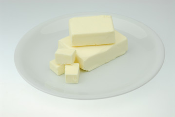 Piece of fresh organic butter on the plate isolated on a gray background in close-up