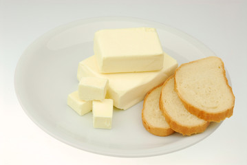 Butter and slices of bread are lying on a plate on a gray isolated background
