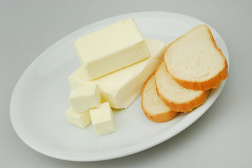 Butter and slices of bread are lying on a plate on a gray isolated background