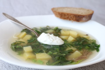 Green summer soup with nettle meat and potatoes with bread on a grey concrete background