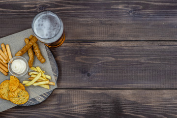 Diverse snacks with beer on dark wooden background. Top view, Empty space for text