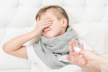 Young boy refuses to take medicine on the bed