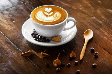 coffee latte art with coffee bean and wood spoon on wood table