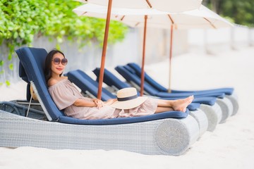 Portrait beautiful young asian woman on the deck chair with umbrella around beach sea ocean for leisure travel