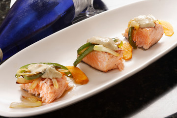 Roasted salmon fillet with almond sauce served with peppers and caramelized onions.