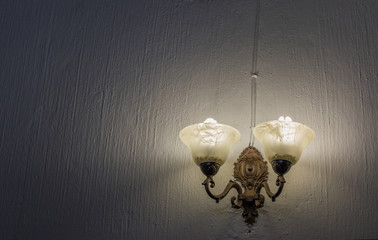 A light mounted on a blank wall casts an eerie shadowy light image in landscape format with copy...
