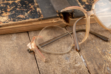 Broken frame from glasses. Old book and glasses.