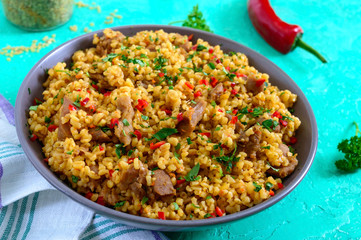 Bulgur with chicken and vegetables. Delicious healthy warm salad on a bright background. Bulgur pilaf. Close up