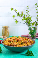 Bulgur with chicken and vegetables. Delicious healthy warm salad on a bright background. Bulgur pilaf