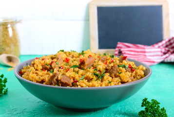 Bulgur with chicken and vegetables. Delicious healthy warm salad on a bright background. Bulgur pilaf