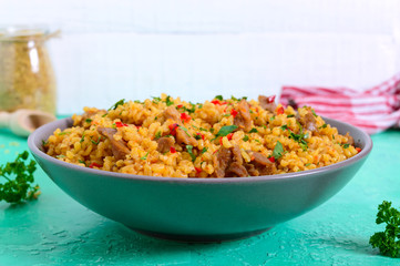 Bulgur with chicken and vegetables. Delicious healthy warm salad on a bright background. Bulgur pilaf