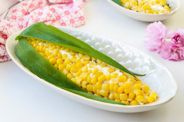 Beautiful salad in the form of corn for the holiday table. Salad of corn, prunes, cheese, eggs in plates on a light background.