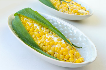 Beautiful salad in the form of corn for the holiday table. Salad of corn, prunes, cheese, eggs in plates on a light background.