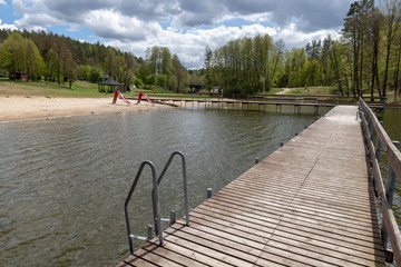 Empty swimming pool in Central Europe. Wooden jetty on the lake.