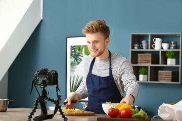 Young male food blogger recording video in kitchen