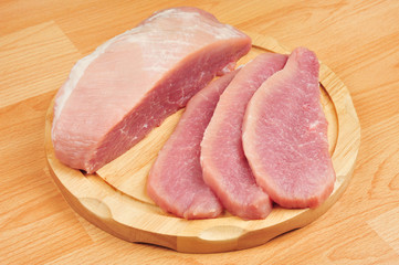 Raw pork meat sliced on a board, on an isolated wooden background